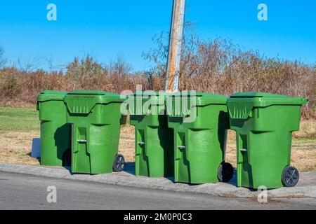 Five green residential trash containers by city street. Stock Photo