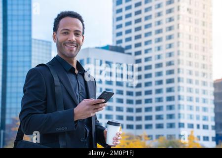 Portrait of successful black businessman in suit smiling looking at camera buildings in background. Stock Photo