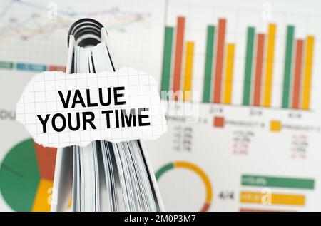 Business concept. On the business charts there is a notebook on which there is a paper plate with the inscription - Value Your Time Stock Photo