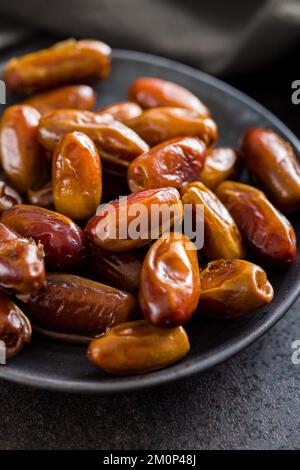 Dried dates fruit on plate on the black table. Stock Photo