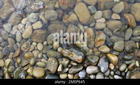 rounded texture stones in transparent water as a natural background, stone space of a sea or river bank in a small amount of water Stock Photo