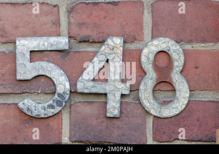 A sign on a wall with the number five hundred forty-eight-548 Stock Photo