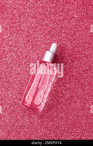Skin care serum in transparent bottle on sparkling background. Beauty and health concept. Mockup for your design with copy space. Flat lay style. Toned image in trendy magenta color of year 2023. Stock Photo