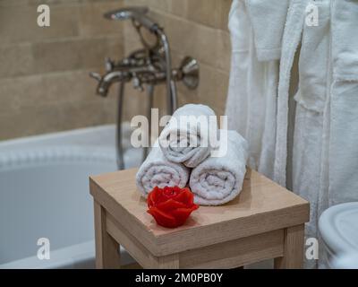Interior of bathroom. White rolled towels. Candle in shape of rose. Stock Photo