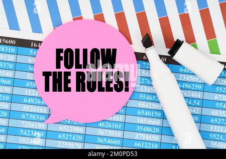 Business and economics concept. On financial statements and charts there is a marker and a sticker with the inscription - FOLLOW THE RULES Stock Photo