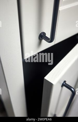 Grey moss solid ash wood painted cupboard cabinet doors modern interior with doorknob black handles, storage or wardrobe ajar opened with metal Stock Photo