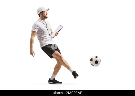 Football coach with a whistle holding a clipboard and kicking a ball isolated on white background Stock Photo