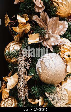 A vertical shot of a Christmas tree decorated in gold shades under the lights Stock Photo