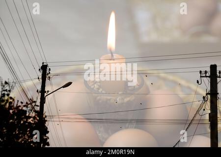 Blackout, power grid overloaded. Blackout concept. Earth hour. Burning flame candle and power lines on background. Energy crisis. Candle flame. Stock Photo