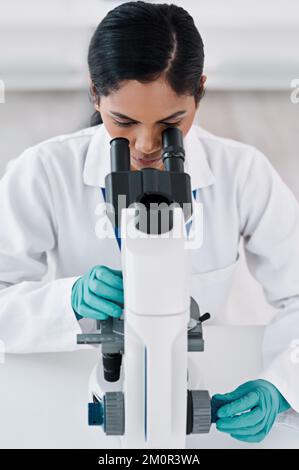 Lets see what we have here...an attractive young female scientist looking through a microscope while working in a laboratory. Stock Photo