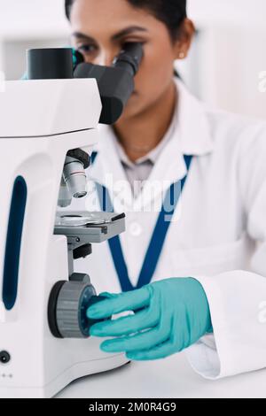 The eye of every scientist. an attractive young female scientist looking through a microscope while working in a laboratory. Stock Photo