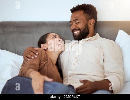 Love, relax and couple in bed in their home, resting and smiling while talking and bonding in bedroom together. Black family, resting and comfort with Stock Photo