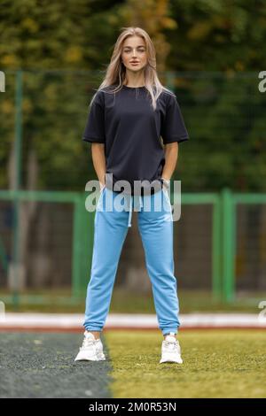 Athletic blonde woman in oversized clothes posing outdoor Stock Photo