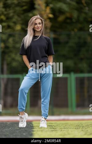 Fit blonde woman in oversized clothes posing outdoor Stock Photo
