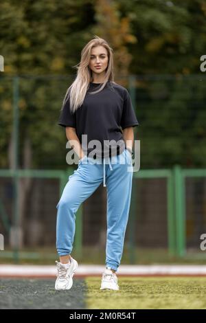 Sporty blonde woman in oversized clothes posing outdoor Stock Photo