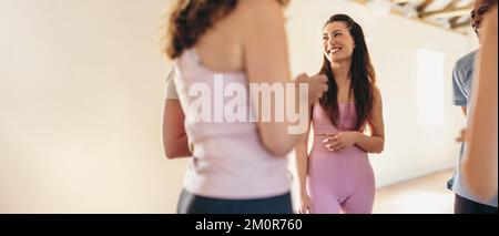 Group of happy fitness people talking to each other while standing in a circle. Multicultural fitness friends sharing mental wellness tips during a cl Stock Photo
