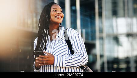 Pensive business woman looking away with a smile while commuting to work in the city. Happy young business woman using a smartphone on her way to the Stock Photo