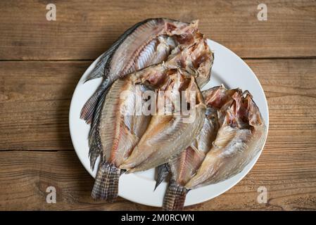 dried fish on white plate, tilapia fish for cooking food on wooden - food preservation dry fish Stock Photo