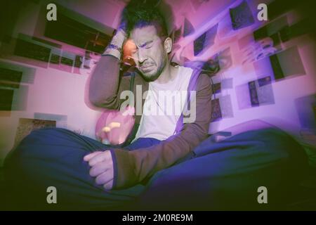 Asian man with mental disorder sitting alone at night and feeling paranoid. Mixed race man mentally ill, feeling depressed and holding his head in his Stock Photo
