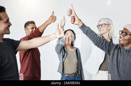 Group happy of diverse businesspeople showing a thumbs up standing together in a meeting in an office at work. Men and woman smiling and holding up a Stock Photo