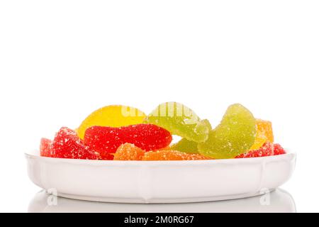 Several sweet marmalade candies on a ceramic white saucer, macro, isolated on white background. Stock Photo