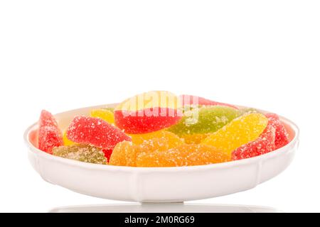 Several sweet marmalade candies on a ceramic white saucer, macro, isolated on white background. Stock Photo