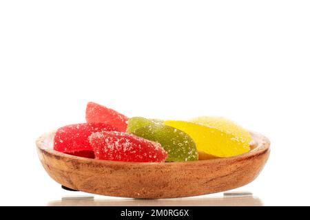 Several sweet marmalade candies on a wooden saucer, macro, isolated on white background. Stock Photo