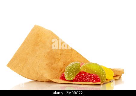 Several sweet marmalade candies on a paper bag, macro, isolated on white background. Stock Photo