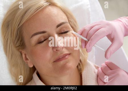 Doctor cosmetologist makes the Rejuvenating facial injections procedure for tightening and smoothing wrinkles on the female woman Stock Photo