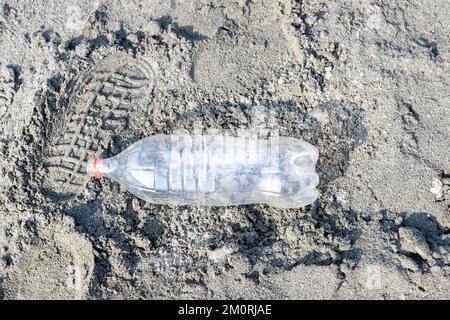 Empty plastic bottle trash laying on a sandy beach. Plastic pollution concept Stock Photo