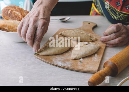 Baker on the table prepares pies stuffed in the bakery top view. Grandma is in the kitchen baking pies. Stock Photo