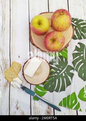 Overhead view of fresh apples with crackers and cream cheese on a table with a monstera napkin Stock Photo