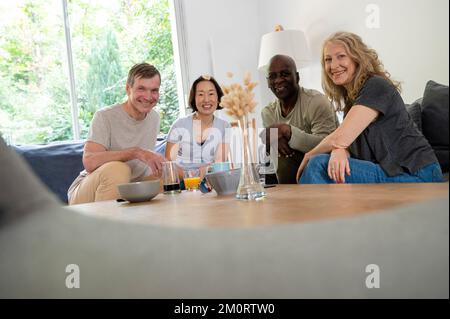 Portrtait of diverse couples looking at camera while gathered at home Stock Photo
