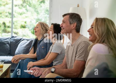 Diverse group of senior friends watching TV at linving room Stock Photo
