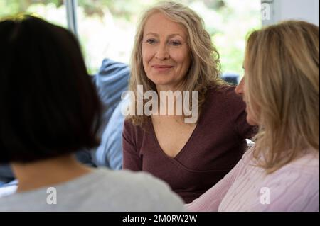 Portrait of senior woman chatting with her two friends at home Stock Photo