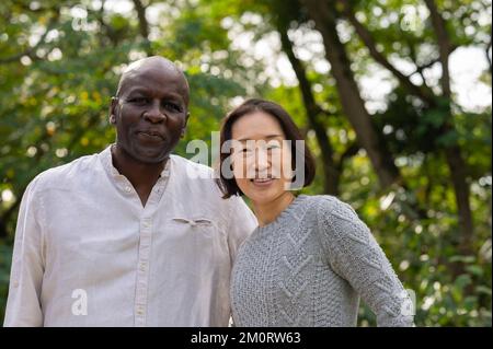 Portrait of middle-age African American man and Asian American woman outdoors in public park Stock Photo
