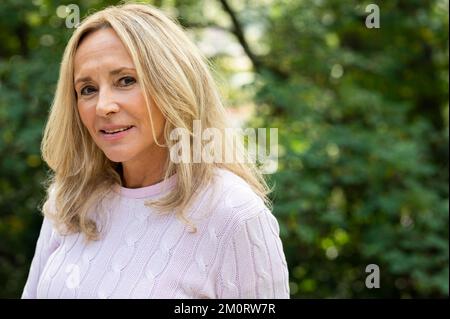 Mid-shot portrait of middle age woman looking at camera while posing outdoors Stock Photo