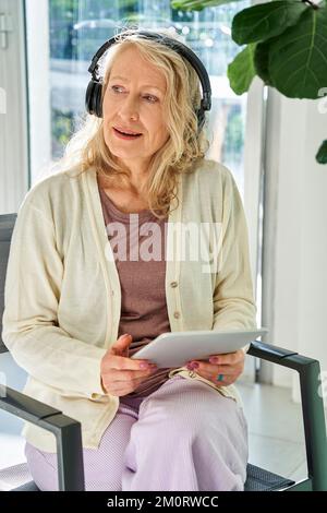 Senior woman listening to music while using digital tablet Stock Photo