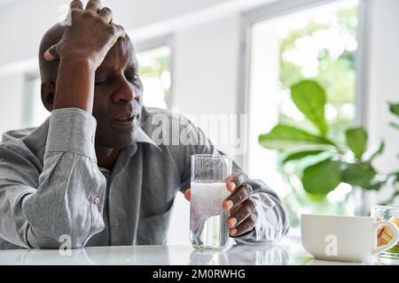 Middle-aged African-American man with headache taking his medicine Stock Photo