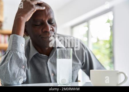 Middle-aged African-American man with headache taking his medicine Stock Photo