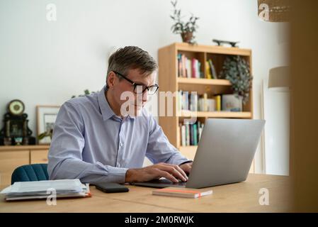 Senior businessman using laptop while working at home Stock Photo