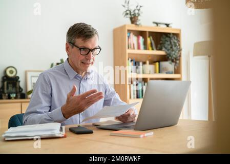 Senior businessman having an online meeting while doing home office Stock Photo