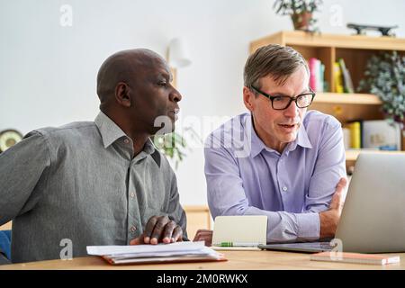 Two mature small company owners discussing business issues in their office Stock Photo