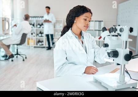 Always inspect every sample thoroughly. a young scientist analysing samples while using a microscope in a lab. Stock Photo