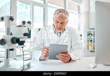 Unravelling the world of science. a senior scientist using a digital tablet in a lab. Stock Photo