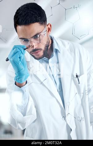 One serious young mixed race male scientist writing and planning on a board wearing glasses and gloves at work. Focused hispanic lab worker drawing a Stock Photo