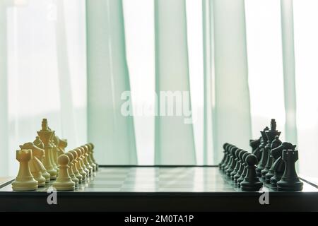 Side view of Chess board ready for the game on the room close to window. Intellectual games and leisure activity concept Stock Photo