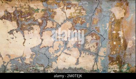 Shot of a wall with cracked plaster - stock photo. Vintage photograph of an old shabby wall with cracks covered with cement - an image for an artistic background. Soft warm light. Stock Photo