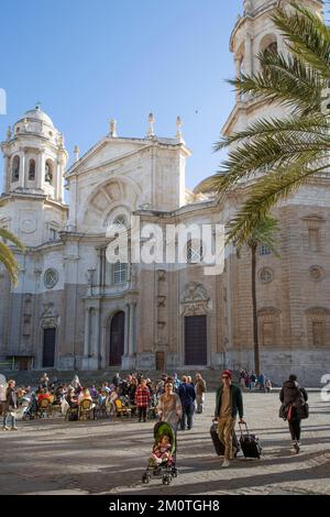Spain, Andalucia, Cadiz, Cathedral Square, young couple in a pushchair and luggage in front of a crowded cafe terrace in front of the baroque facade of the cathedral Stock Photo