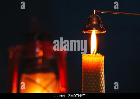 A burning candle on the background of a kerosene lamp. Festive arrival. Beautiful handmade candles. Cozy atmosphere in the house Stock Photo